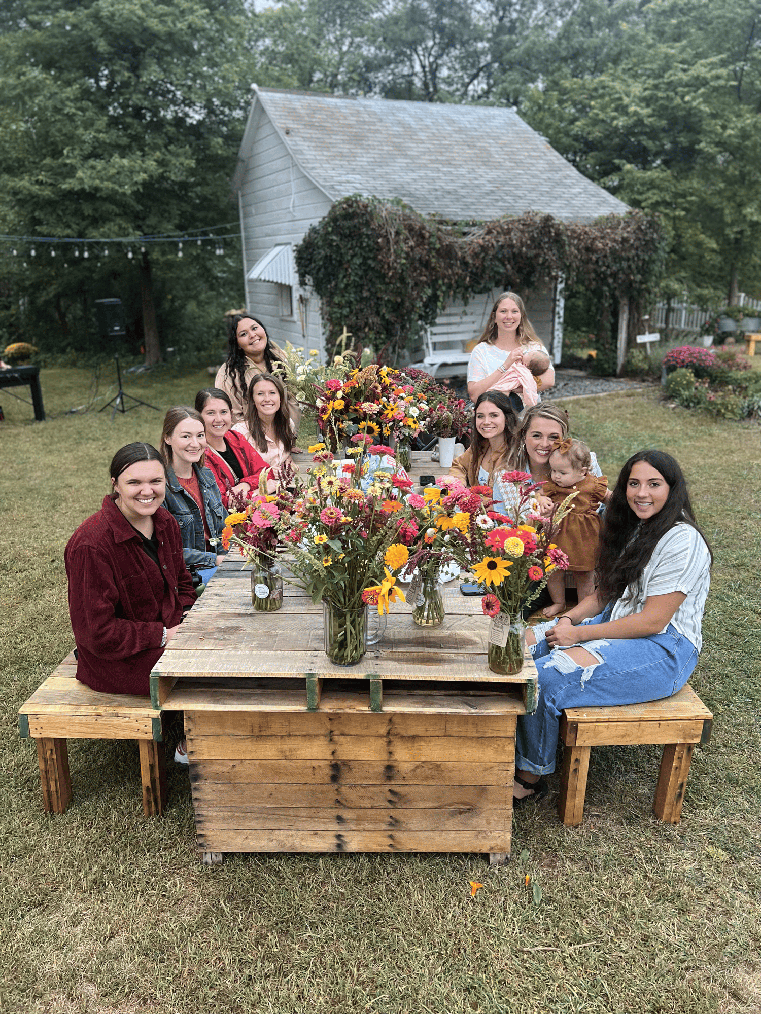 Image of the attendees at a private workshop. All are smiling and showing off their arrangements.