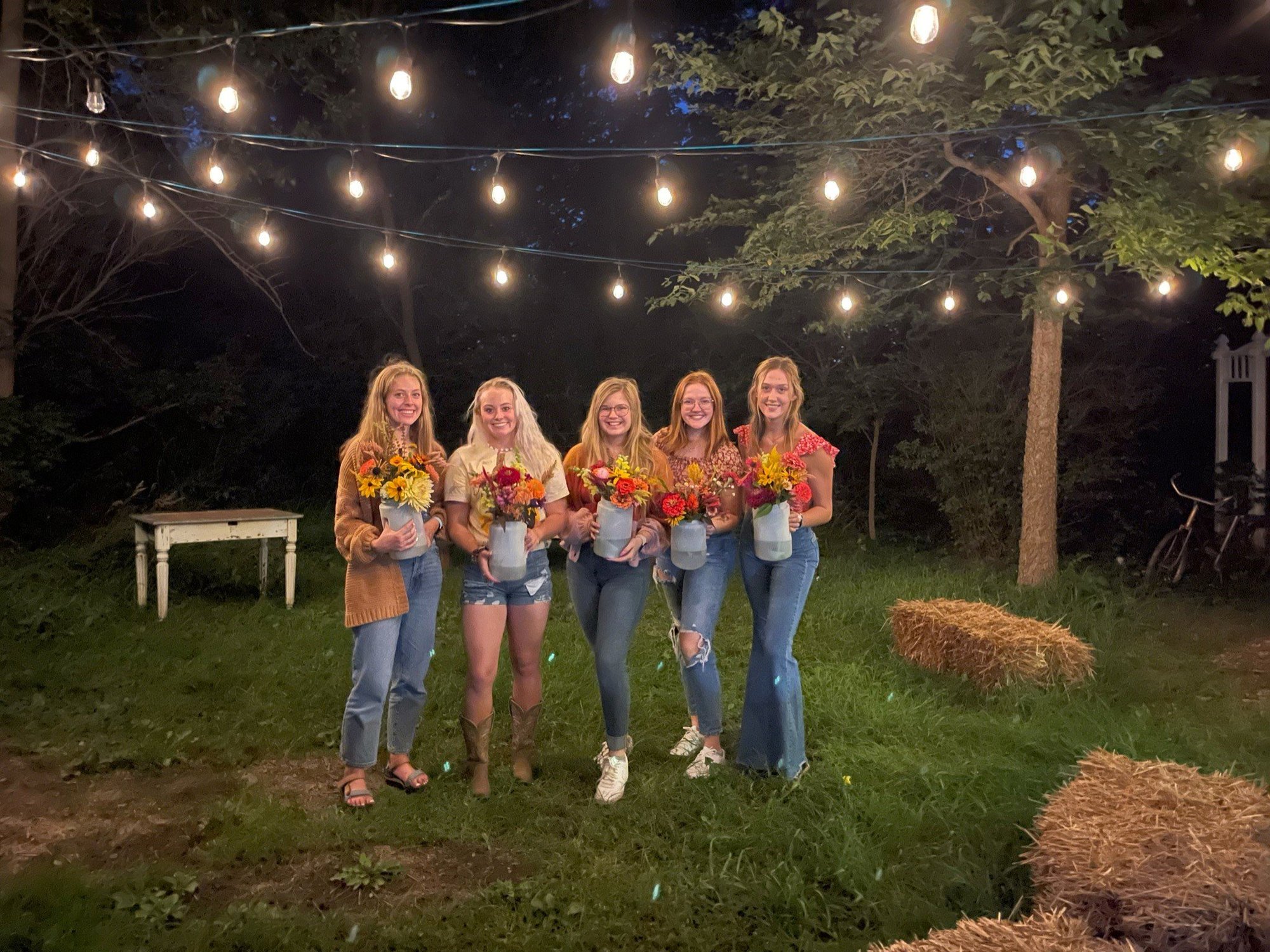 A group of ladies each holding their containers of flowers after a make & take class.