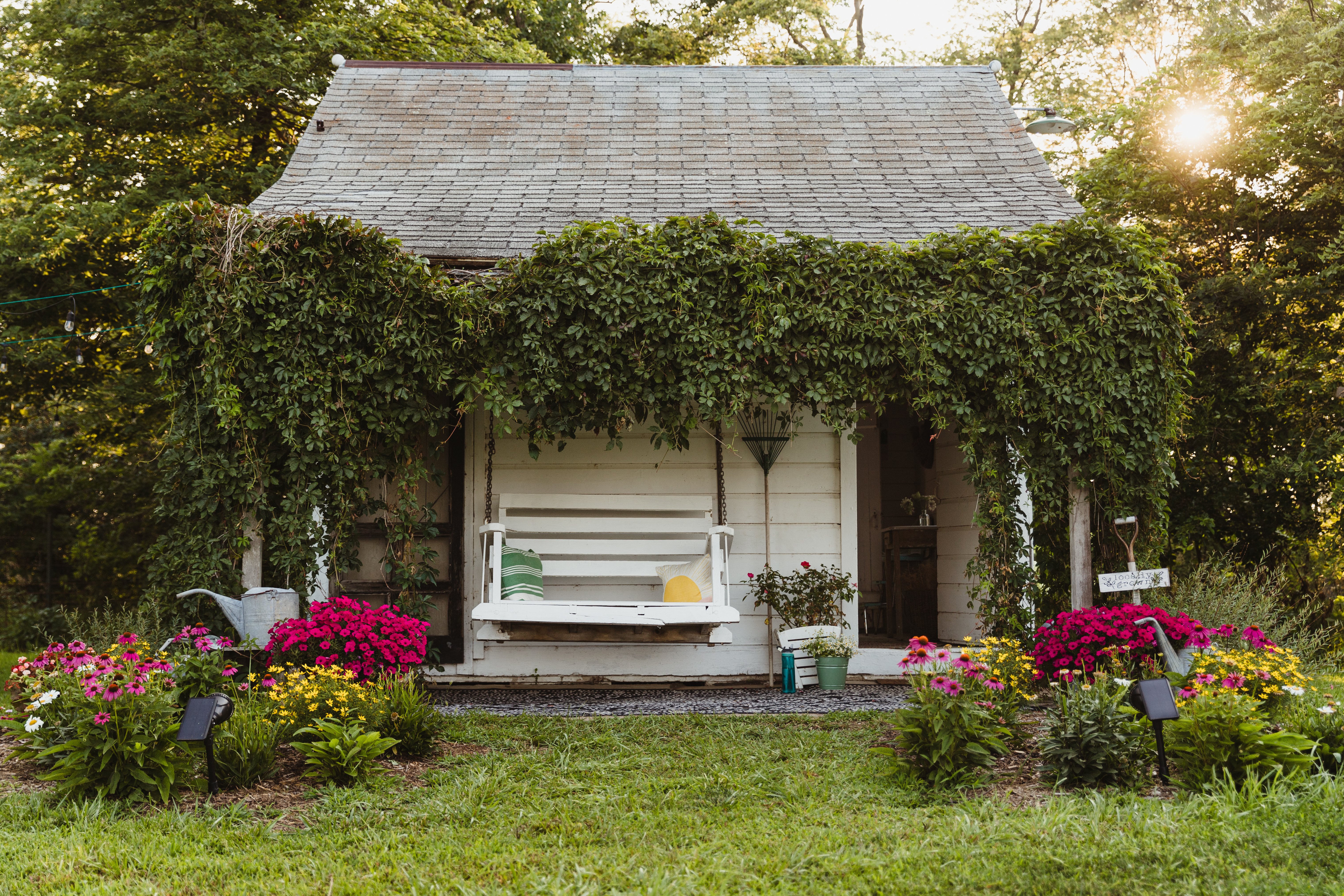 Thelma's charming summer kitchen. The serene porch covered in greenery and a white porch swing complete the cozy feel.